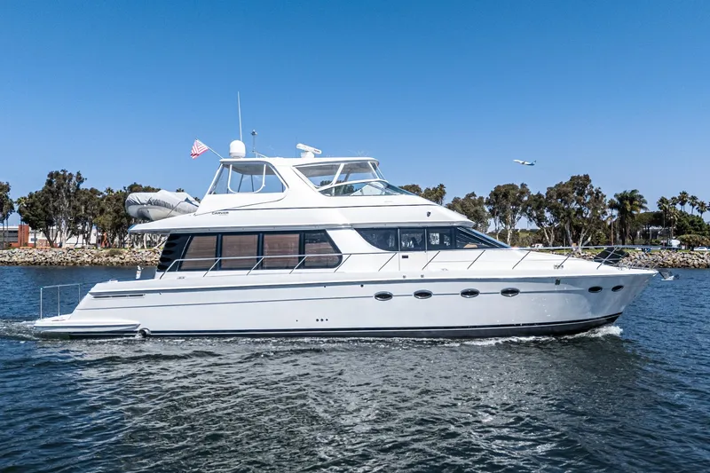  Yacht Photos Pics 2003 Carver 570 Voyager Pilothouse yacht cruising on a sunny day near the shoreline.