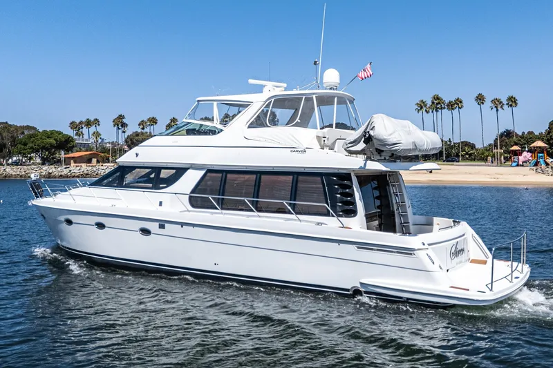  Yacht Photos Pics 2003 Carver 570 Voyager Pilothouse yacht cruising near a sandy beach with palm trees.