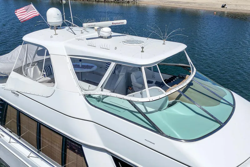  Yacht Photos Pics 2003 Carver 570 Voyager Pilothouse yacht on calm water, featuring a sleek design and American flag.
