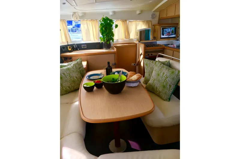 Rewind Yacht Photos Pics Interior of 2007 Lagoon 440 catamaran with dining table, cushions, and kitchen area.