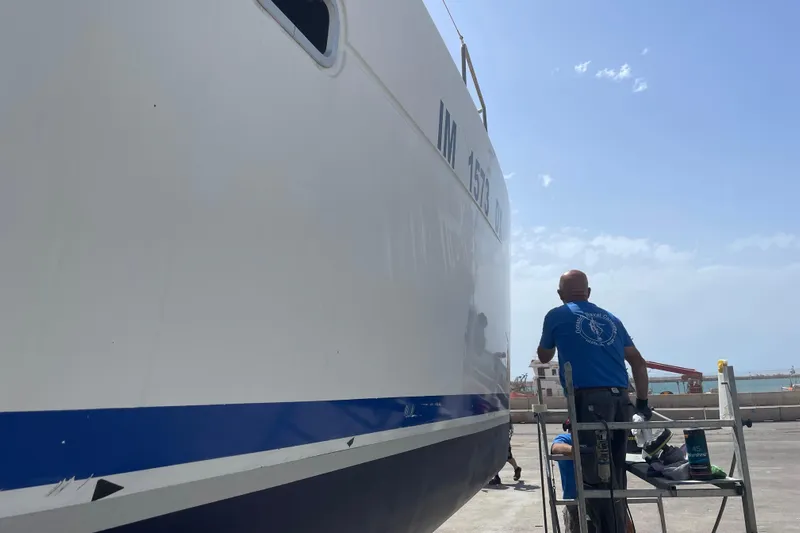 Rewind Yacht Photos Pics Person working on a 2007 Lagoon 440 catamaran hull in a shipyard.