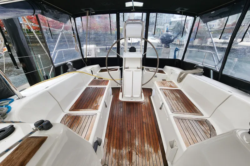 Danza Yacht Photos Pics 2007 Hanse 400e yacht cockpit with wooden seating and steering wheel, docked in marina.