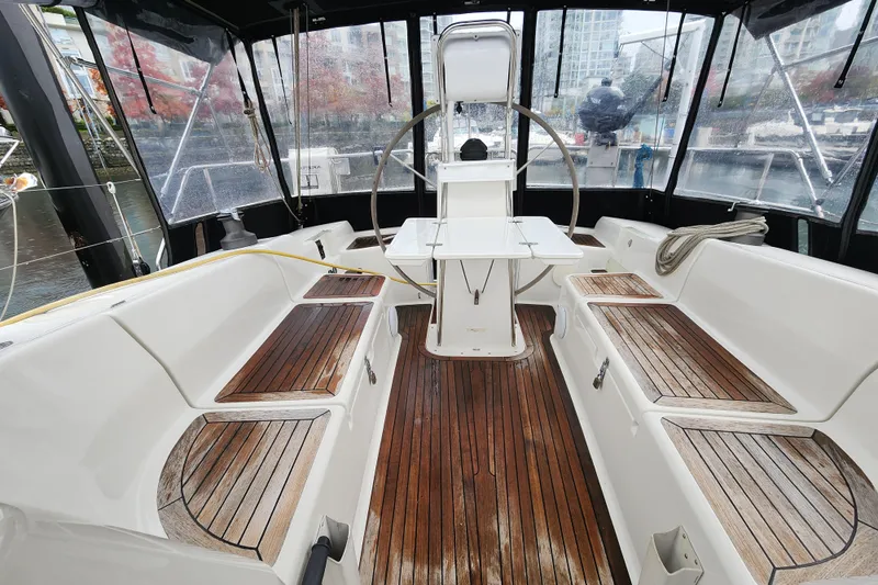Danza Yacht Photos Pics 2007 Hanse 400e yacht cockpit with wooden seating and steering wheel, docked in a marina.