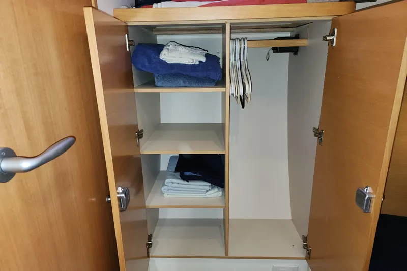 Danza Yacht Photos Pics Open wooden closet with shelves, hangers, and folded clothes on a 2007 Hanse 400e.