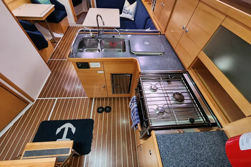Danza Yacht Photos Pics Interior of 2007 Hanse 400e yacht kitchen with stove, sink, and wooden cabinetry.