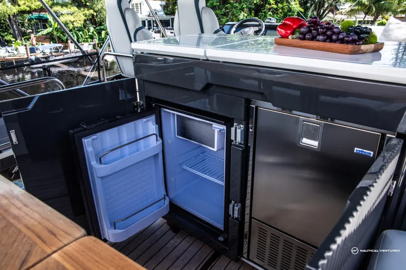 Fairline Phantom Yacht Photos Pics Open mini fridge on Fairline Phantom 65 yacht, 2023 model, with fruit platter on counter.