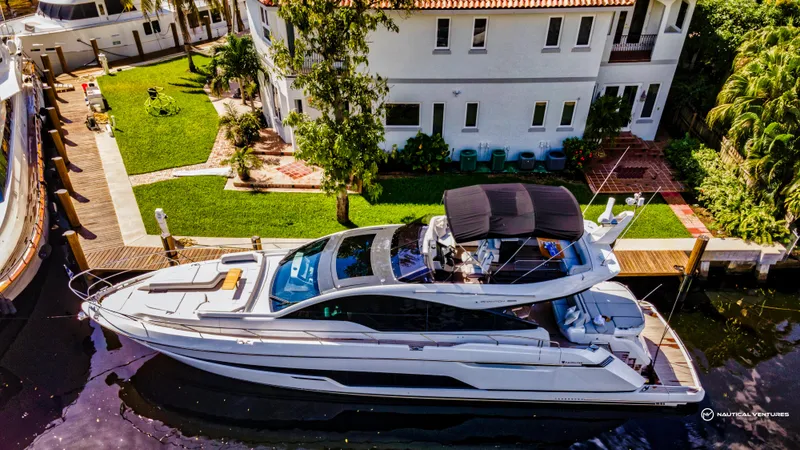 Fairline Phantom Yacht Photos Pics 2023 Fairline Phantom 65 yacht docked near a waterfront property.