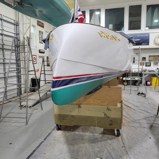 Patience Yacht Photos Pics Custom M27 boat in workshop, 2023 model, with vibrant hull colors and gold lettering.