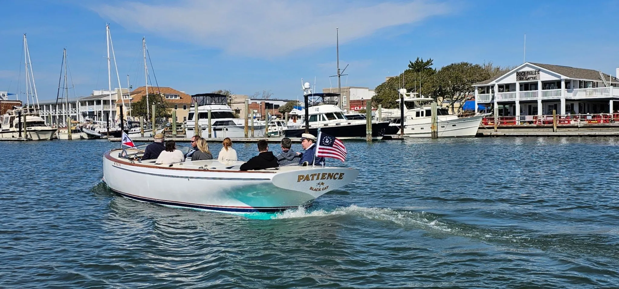 A custom 2023 M27 boat named "Patience" cruising in a marina with passengers.