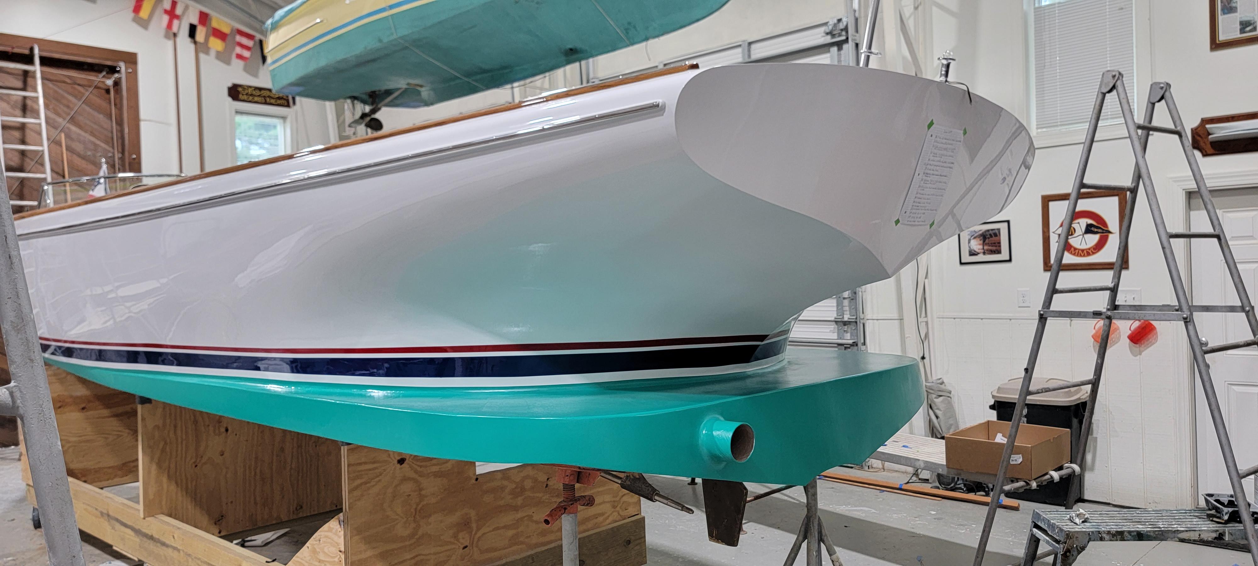 Custom M27 boat in workshop, 2023 model, with teal and white hull.