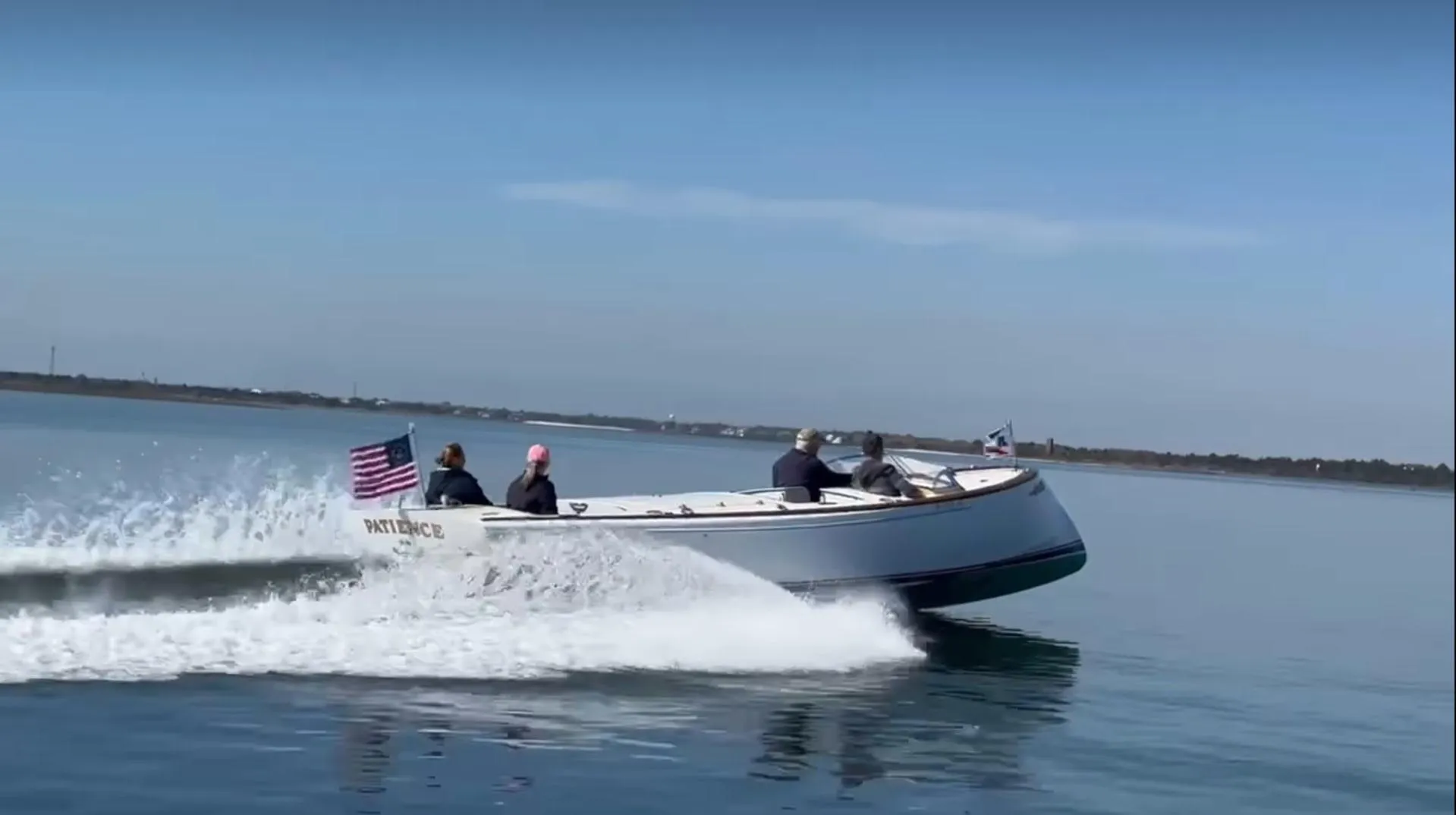 Custom M27 boat cruising on calm water, 2023 model, with passengers and an American flag.