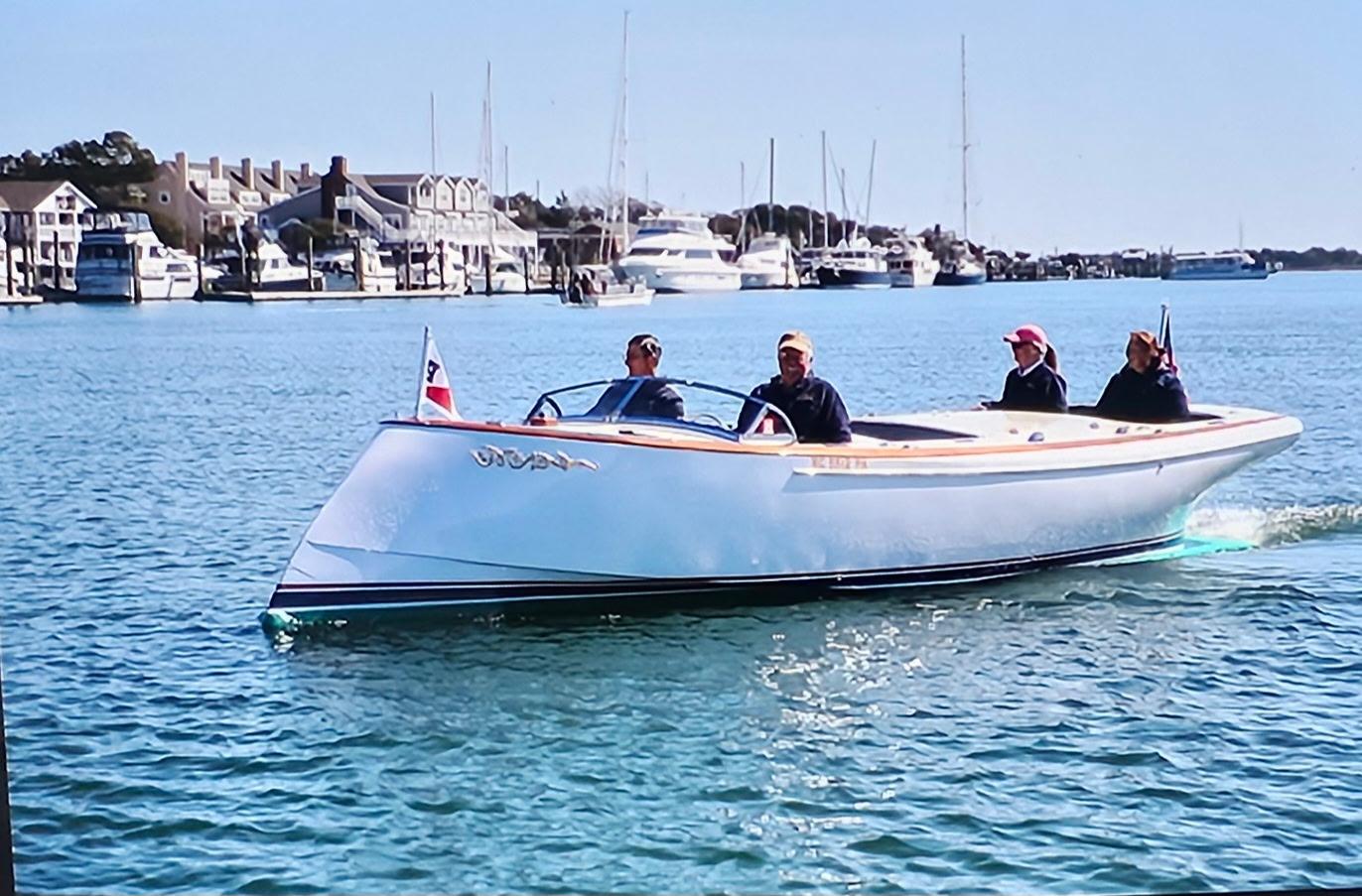 Custom M27 boat cruising in a marina, 2023 model, with passengers enjoying the ride.