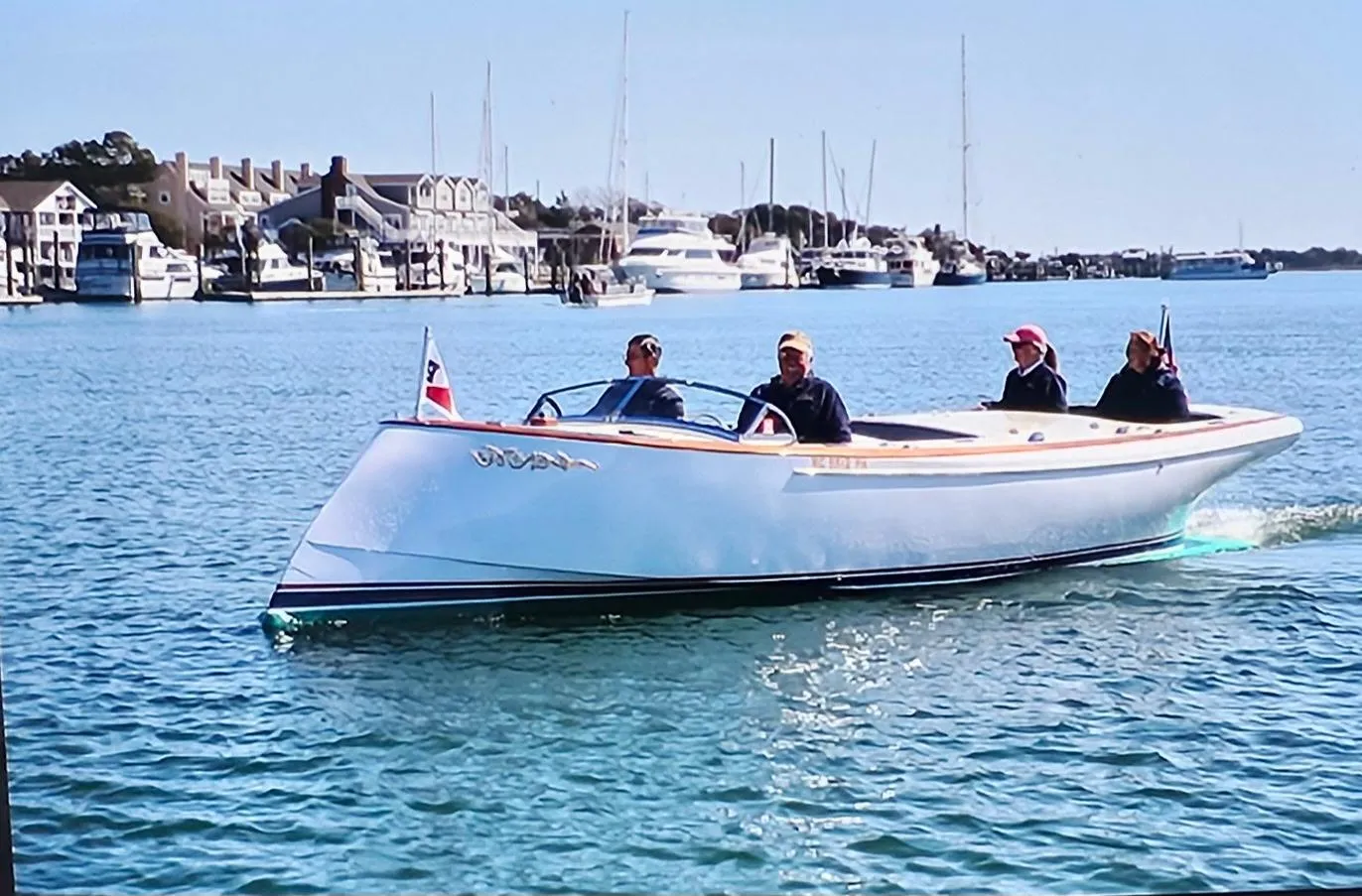 Custom M27 boat cruising in a marina, 2023 model, with passengers enjoying the ride.