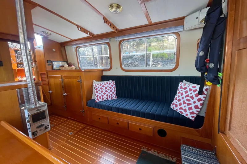 Honu Yacht Photos Pics Cozy interior of 1994 Eagle 40 Pilothouse Trawler with wood finish and blue seating.