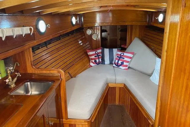 Ilona Yacht Photos Pics Cozy wooden boat interior with cushioned seating, nautical decor, and a small sink. Custom Gannon & Benjamin, 2005.