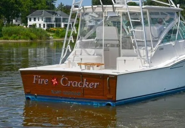 Fire Cracker Yacht Photos Pics 2007 Cabo 35 Express boat named "Fire Cracker" on calm water near shoreline.