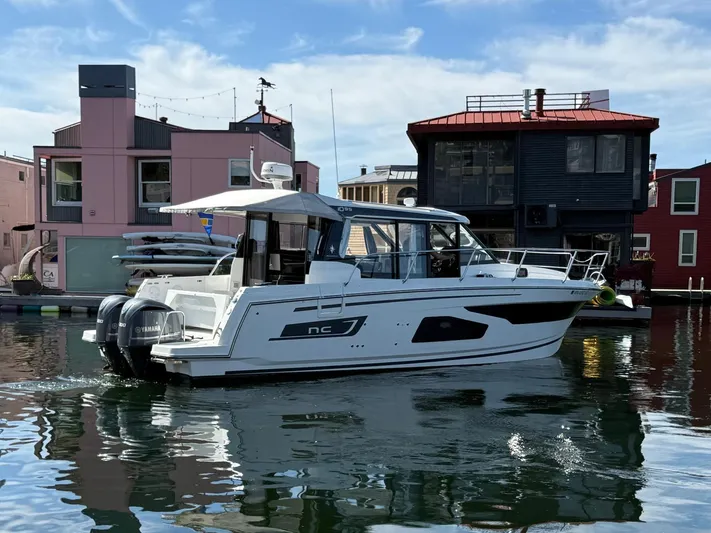  Yacht Photos Pics 2021 Jeanneau NC Weekender 1095 boat docked near colorful waterfront buildings.