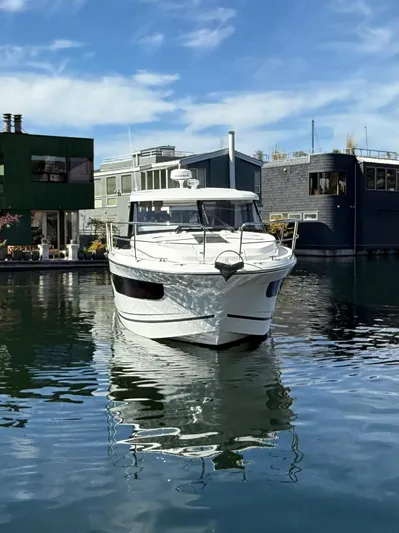  Yacht Photos Pics 2021 Jeanneau NC Weekender 1095 boat docked on calm water, surrounded by modern houseboats.