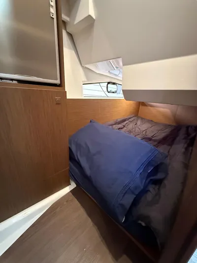  Yacht Photos Pics 2021 Jeanneau NC Weekender 1095 cabin interior with cozy bedding and wooden finish.