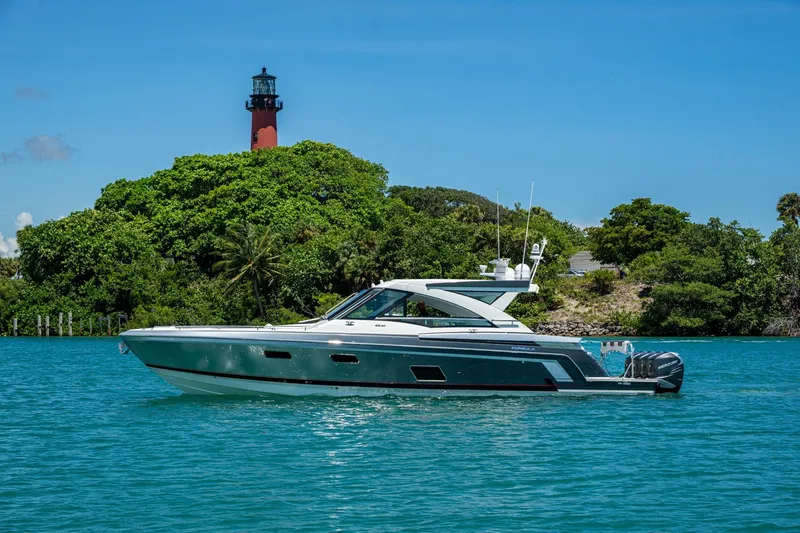  Yacht Photos Pics 2019 Formula 430 Super Sport Crossover yacht cruising near a lush island with a lighthouse.