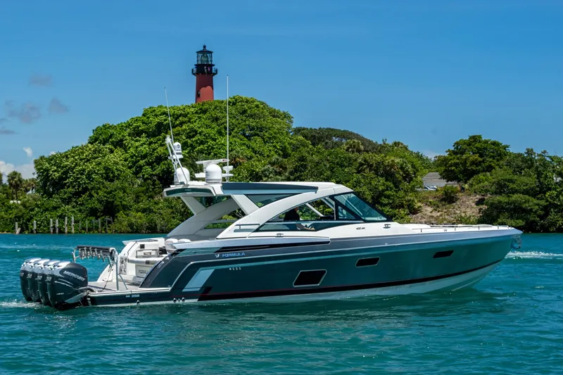  Yacht Photos Pics 2019 Formula 430 Super Sport Crossover yacht cruising near a lush island and lighthouse.