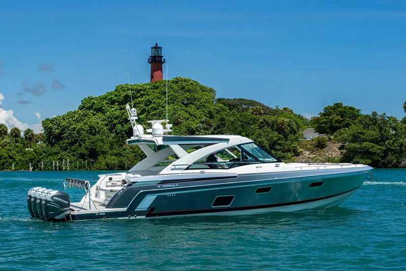  Yacht Photos Pics 2019 Formula 430 Super Sport Crossover yacht cruising near a lush island with a lighthouse.