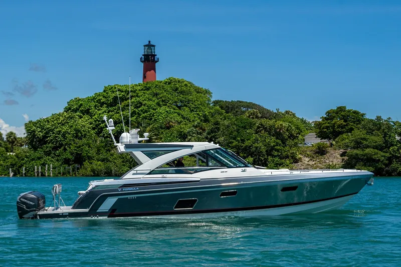  Yacht Photos Pics 2019 Formula 430 Super Sport Crossover yacht cruising near a lush island with a lighthouse.