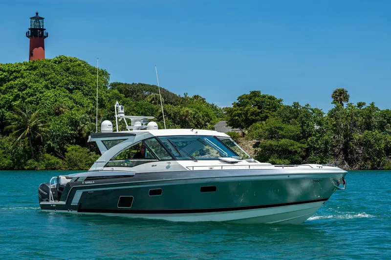  Yacht Photos Pics 2019 Formula 430 Super Sport Crossover cruising near lush greenery and a lighthouse.