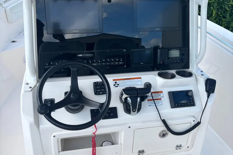  Yacht Photos Pics 2022 Cobia 280 Center Console helm with steering wheel, controls, and navigation screens.