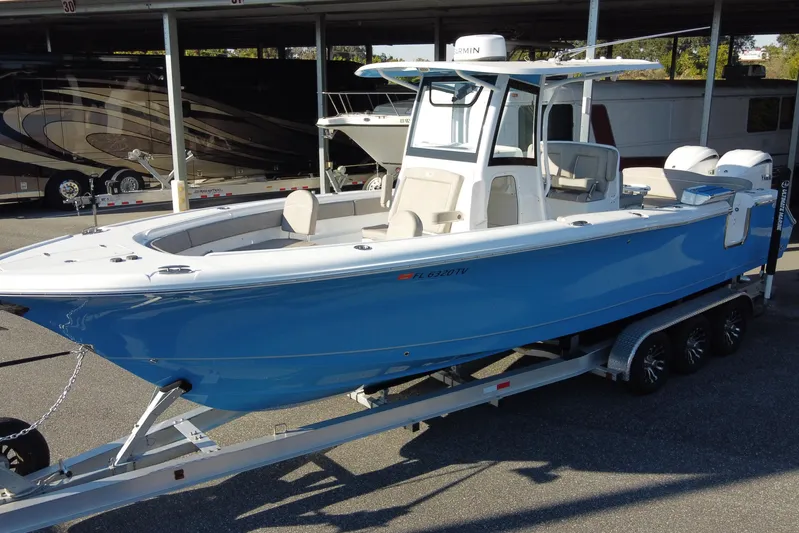  Yacht Photos Pics 2024 Sea Hunt Ultra 305 SE boat on trailer, blue hull, parked outdoors.