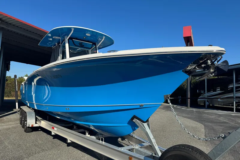  Yacht Photos Pics 2024 Sea Hunt Ultra 305 SE boat on trailer, vibrant blue hull, parked outdoors.