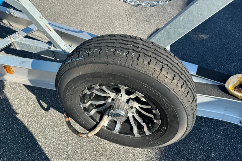  Yacht Photos Pics Trailer wheel of 2024 Sea Hunt Ultra 305 SE boat on asphalt surface.