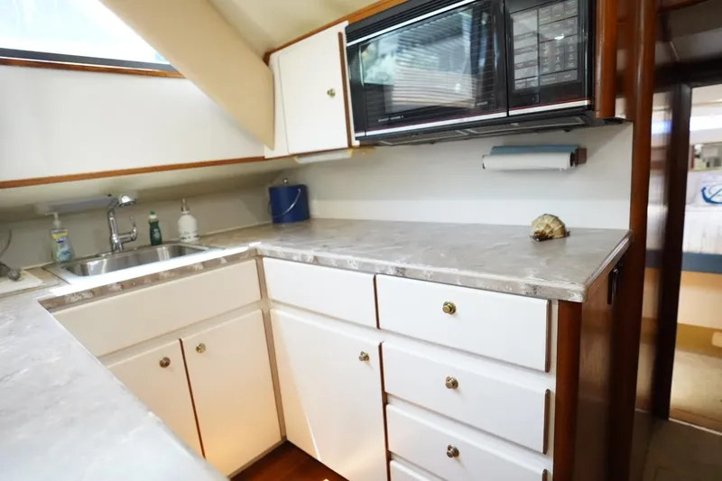 Relentless Yacht Photos Pics Compact kitchen in 1993 Tiara Yachts 4300 Convertible with sink, microwave, and storage cabinets.