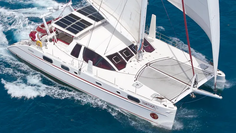Tortuga Yacht Photos Pics Catana 582 catamaran sailing on blue ocean, 2001 model, featuring solar panels and spacious deck.