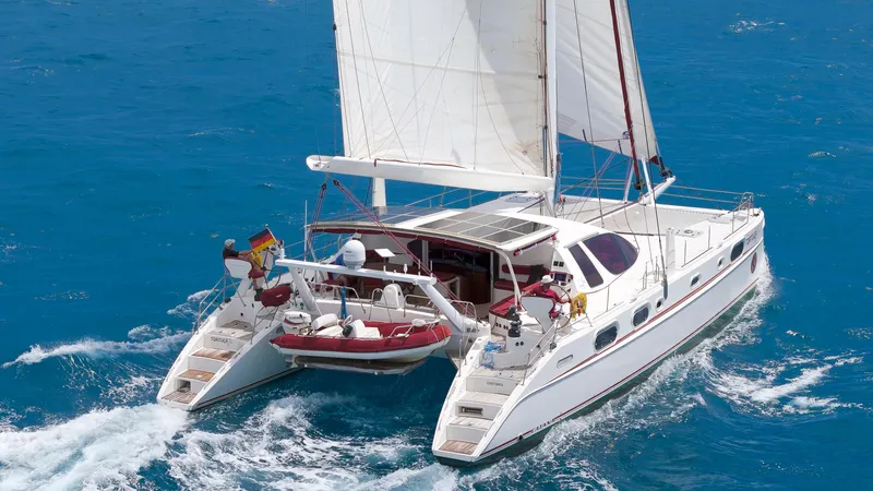 Tortuga Yacht Photos Pics Catana 582 catamaran sailing on blue ocean, 2001 model, with white sails and red dinghy.