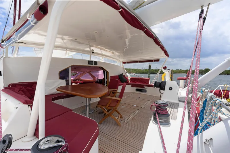 Tortuga Yacht Photos Pics Catana 582 yacht deck, 2001 model, featuring red seating and wooden table.