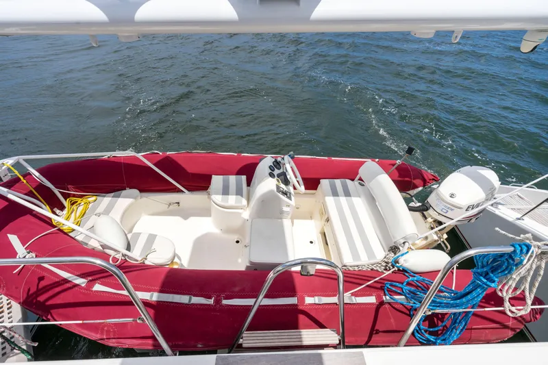 Tortuga Yacht Photos Pics Red inflatable boat with white seats and motor, docked on water. Catana 582, 2001 model.