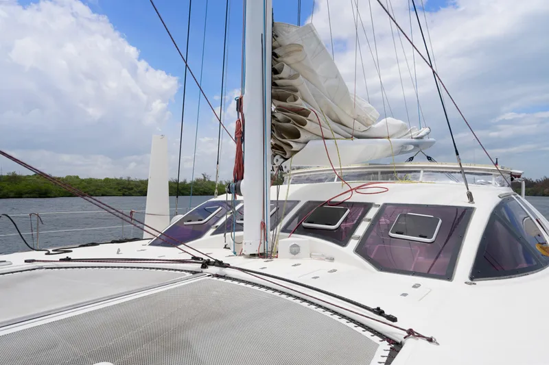 Tortuga Yacht Photos Pics 2001 Catana 582 catamaran with sails down, docked by a scenic waterway.