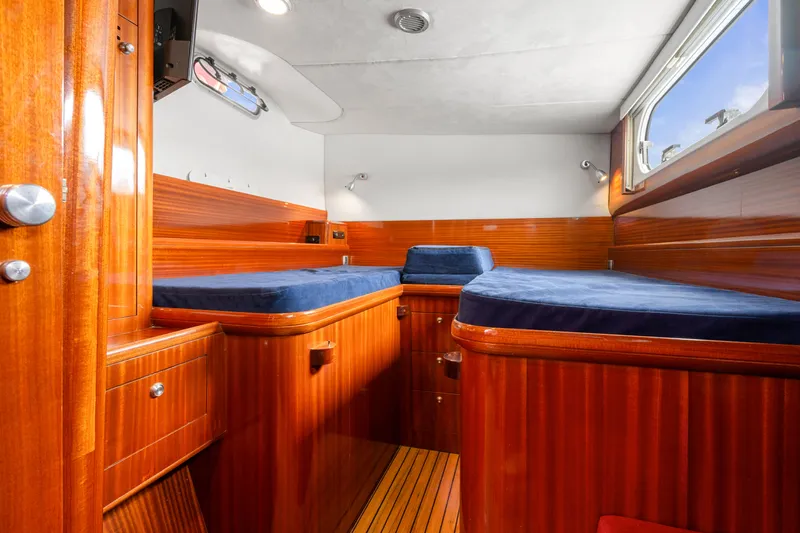 Tortuga Yacht Photos Pics Interior of 2001 Catana 582 yacht cabin with wooden finish and blue bedding.