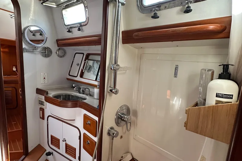 Eos Yacht Photos Pics Compact bathroom in a 2006 Passport 470 yacht, featuring a sink, shower, and wooden accents.