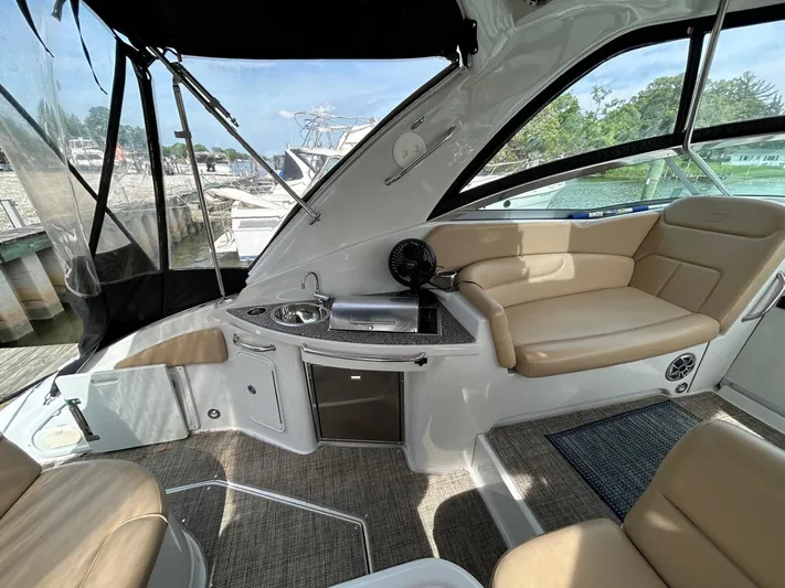  Yacht Photos Pics 2015 Crownline 350 SY yacht interior with seating, kitchenette, and windows overlooking marina.