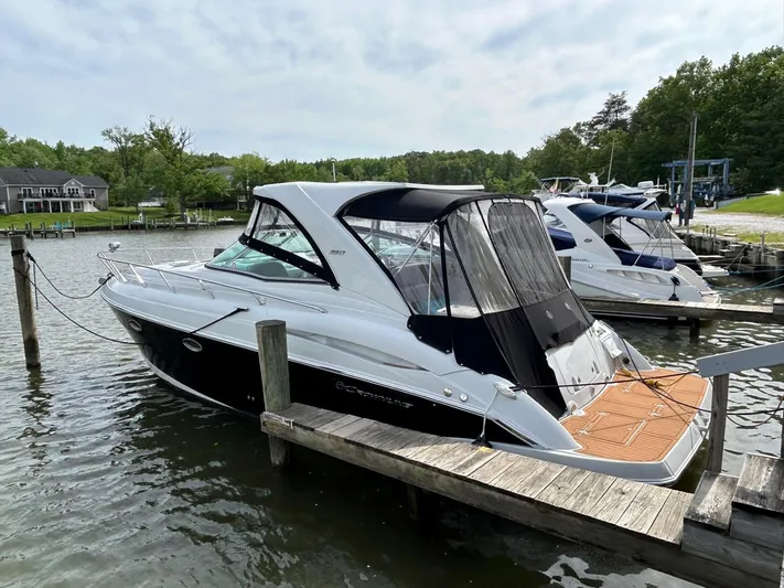  Yacht Photos Pics 2015 Crownline 350 SY boat docked at a marina, surrounded by calm water and greenery.