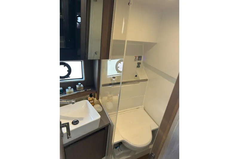  Yacht Photos Pics Modern bathroom in 2022 Sealine C335V yacht, featuring sink, toilet, and window.
