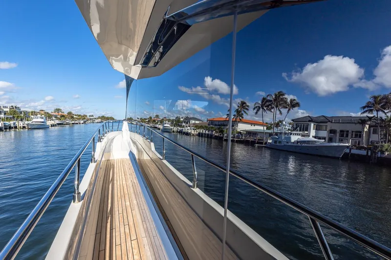  Yacht Photos Pics 2024 Astondoa 66 Flybridge yacht on a sunny waterfront, reflecting clear blue skies.