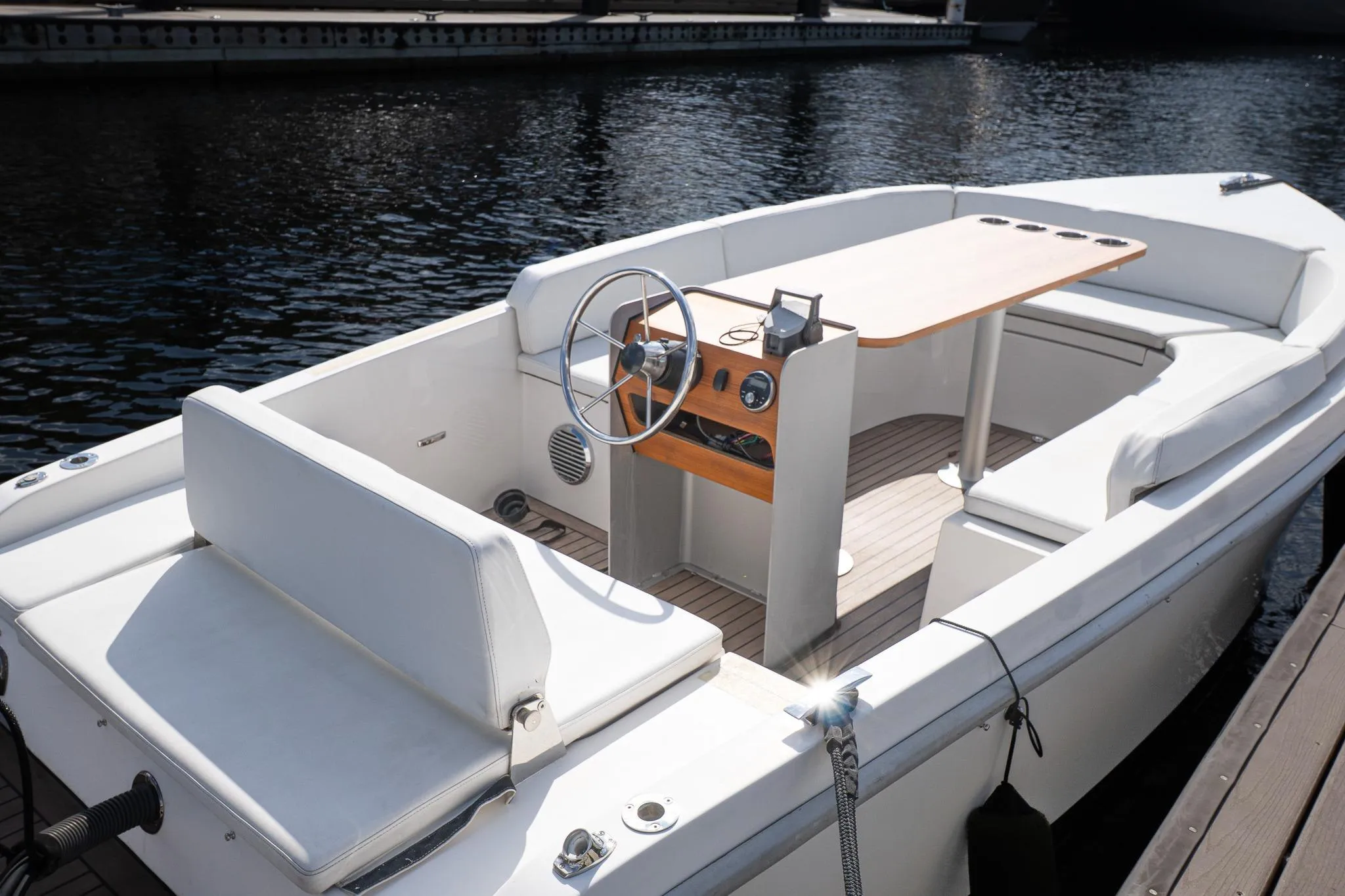2022 Rand 18 Picnic boat with sleek white interior and wooden accents, docked on calm water.