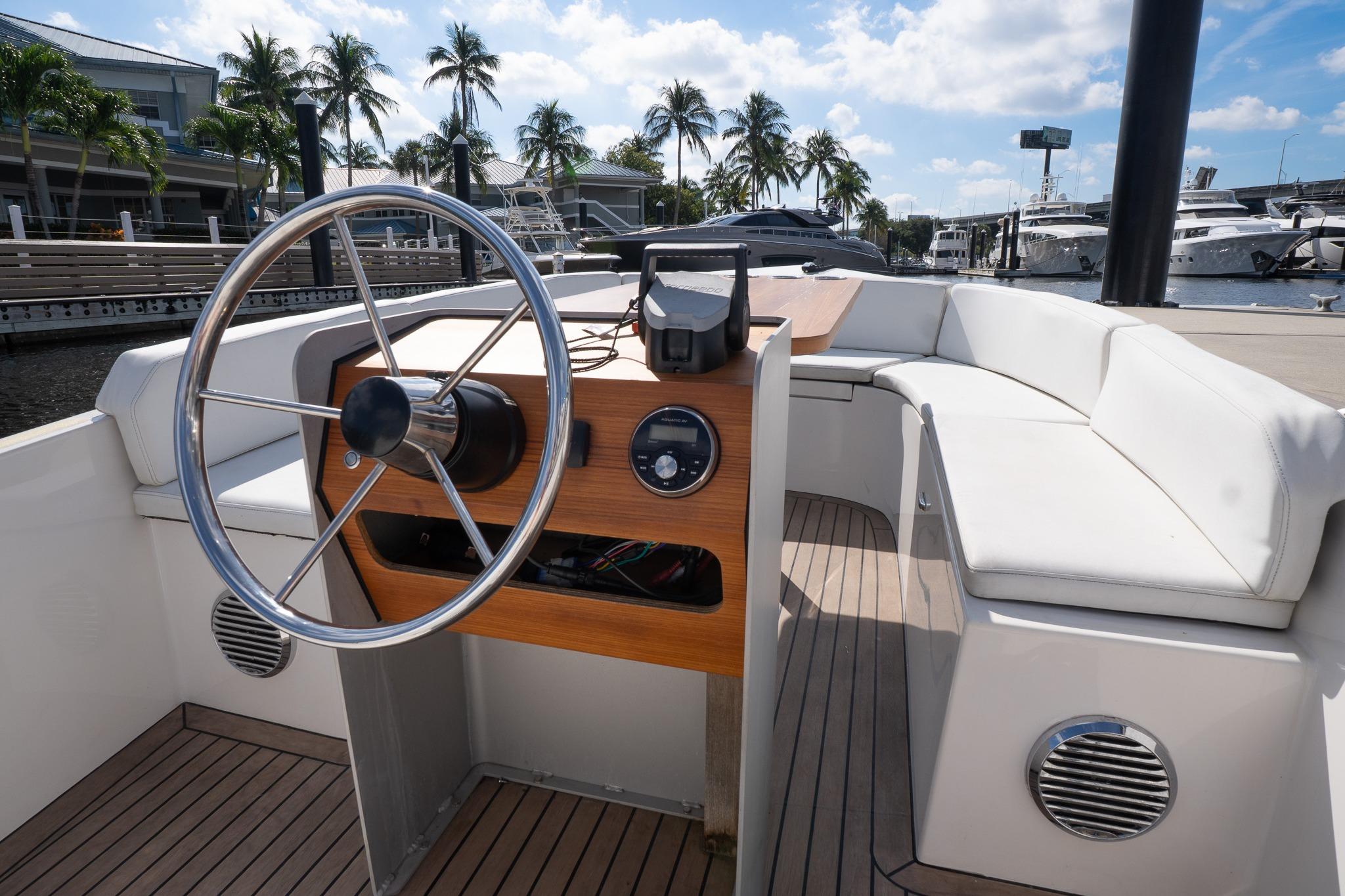 2022 Rand 18 Picnic boat interior with steering wheel, white seating, and wooden dashboard.