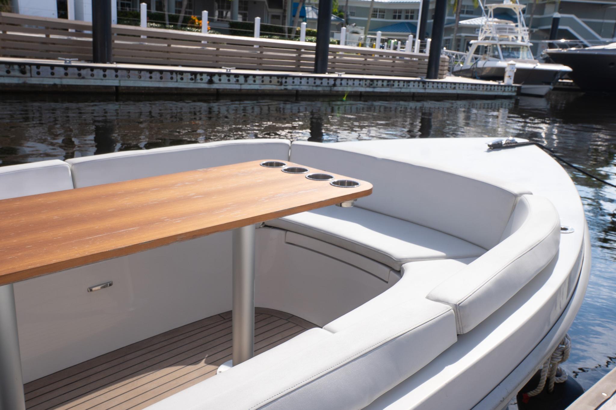 2022 Rand 18 Picnic boat with wooden table and cushioned seating at a marina.