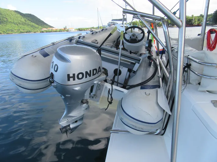 Lady Ana Yacht Photos Pics Inflatable boat with Honda outboard motor on a Bali 4.1 catamaran, docked by lush green hills.