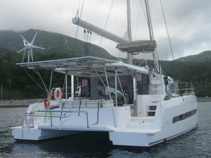 Lady Ana Yacht Photos Pics 2020 Bali 4.1 catamaran docked near lush green mountains, featuring a wind turbine.