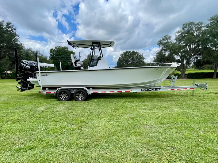  Yacht Photos Pics 2021 Orion 29CC boat on trailer, parked on grass under cloudy sky.